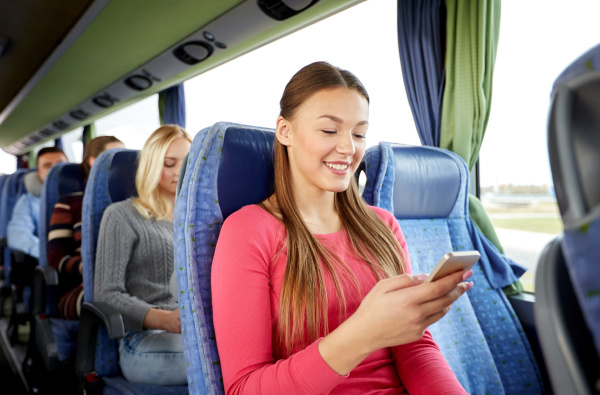 glueckliche frau im reisebus mit smartphone