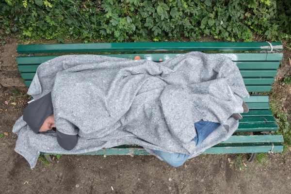 obdachloser mann schlaeft auf bank