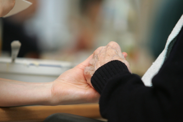 pflegekraft gibt senior die hand