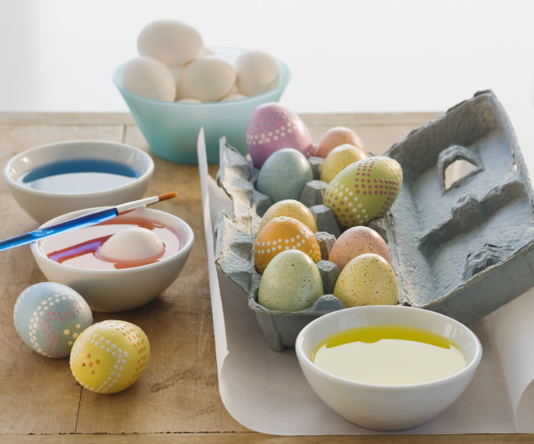 dekorierte eier neben schuesseln mit farbstoff