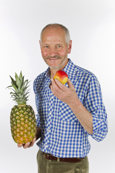 aelterer mann mit ananas und apfel