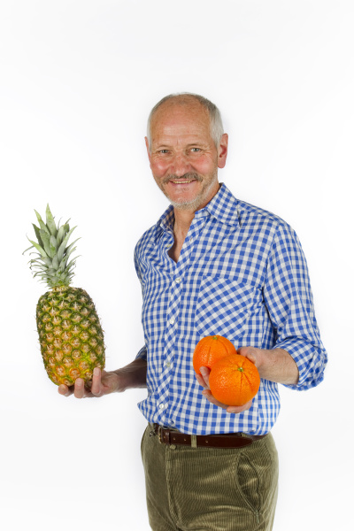 aelterer mann mit ananas und orangen