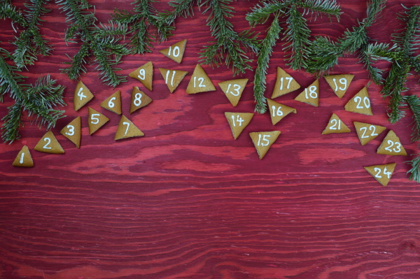24 adventskekse auf rotem holz mit