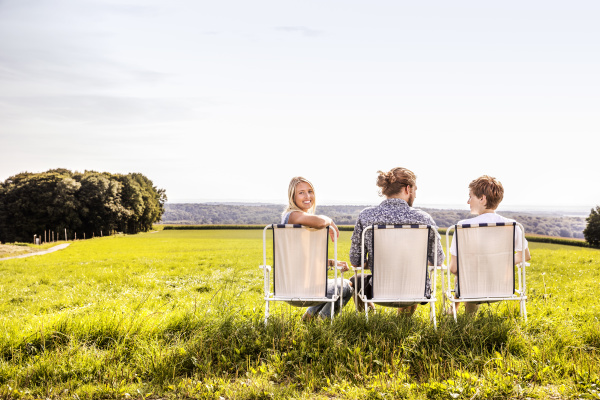freunde sitzen auf campingstuehlen in laendlicher