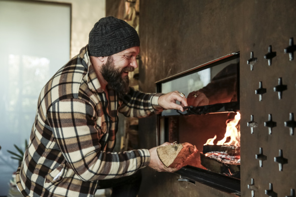 gluecklicher baertiger mann vor kamin zu