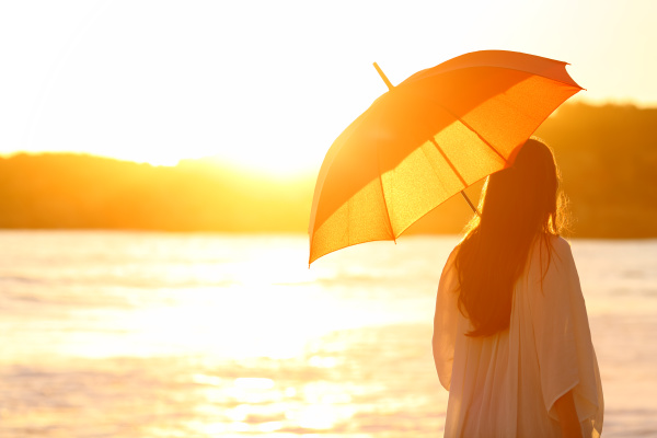 frau mit sonnenschirm bei sonnenuntergang am
