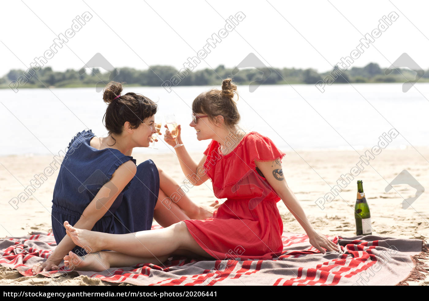 Zwei Lächelnde Freunde Sitzen Am Strand Und Stoßen Lizenzfreies Bild 20206441 Bildagentur 