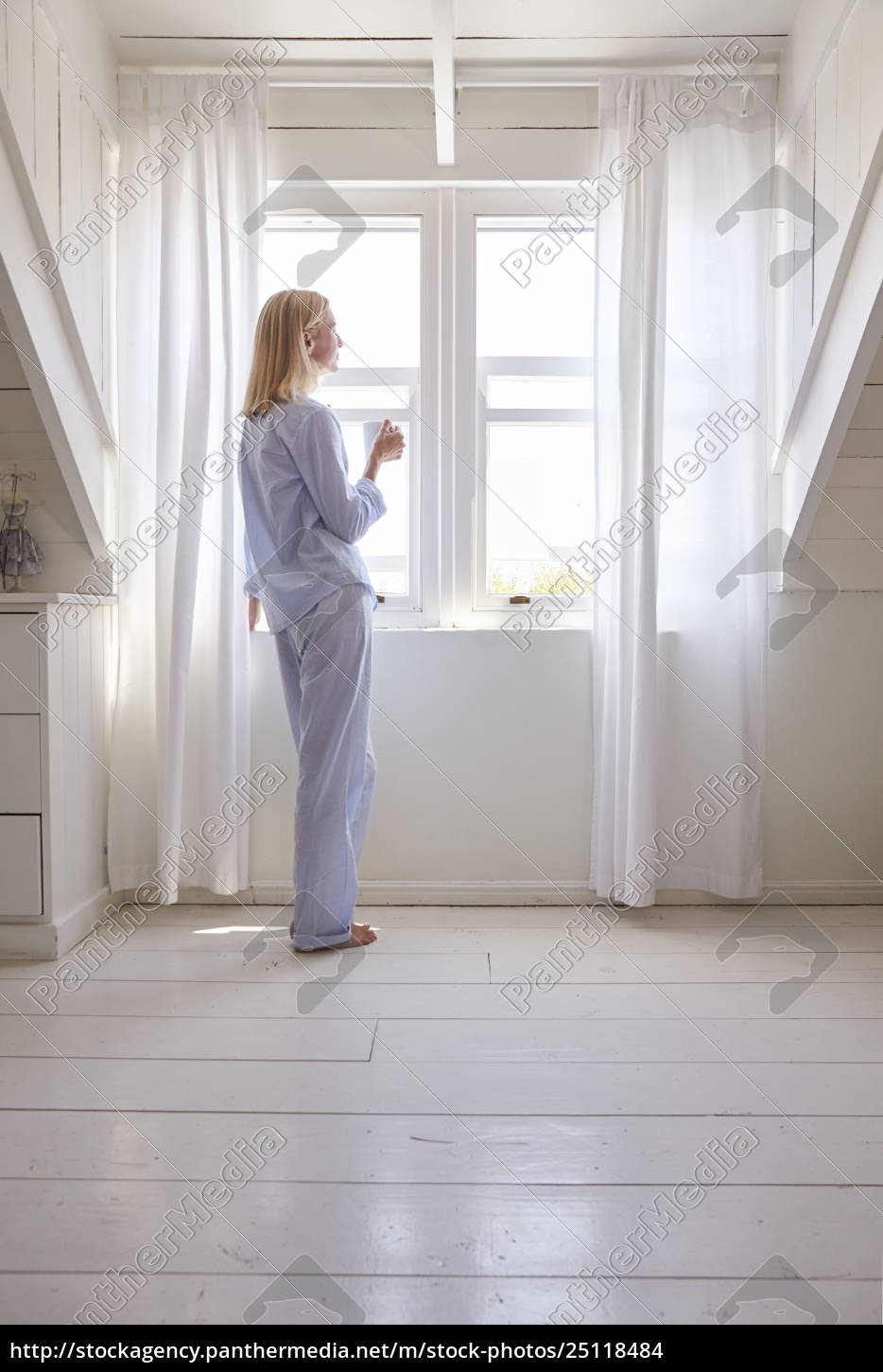 Lizenzfreies Foto 25118484 Woman Standing By Bedroom Window With Hot Drink