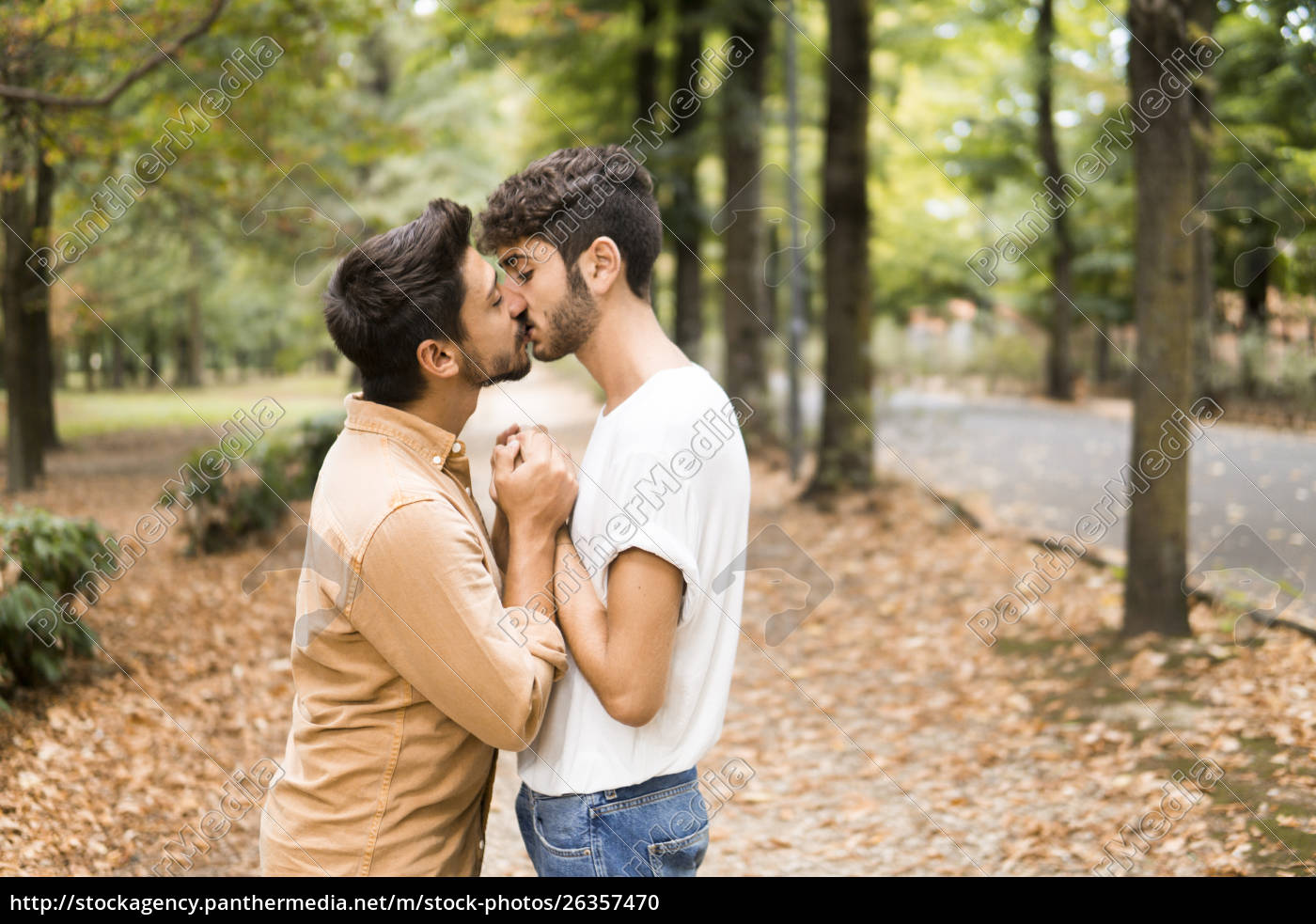 Junges schwules Paar hält Hände und küsst im Herbst Foto Foto Bild