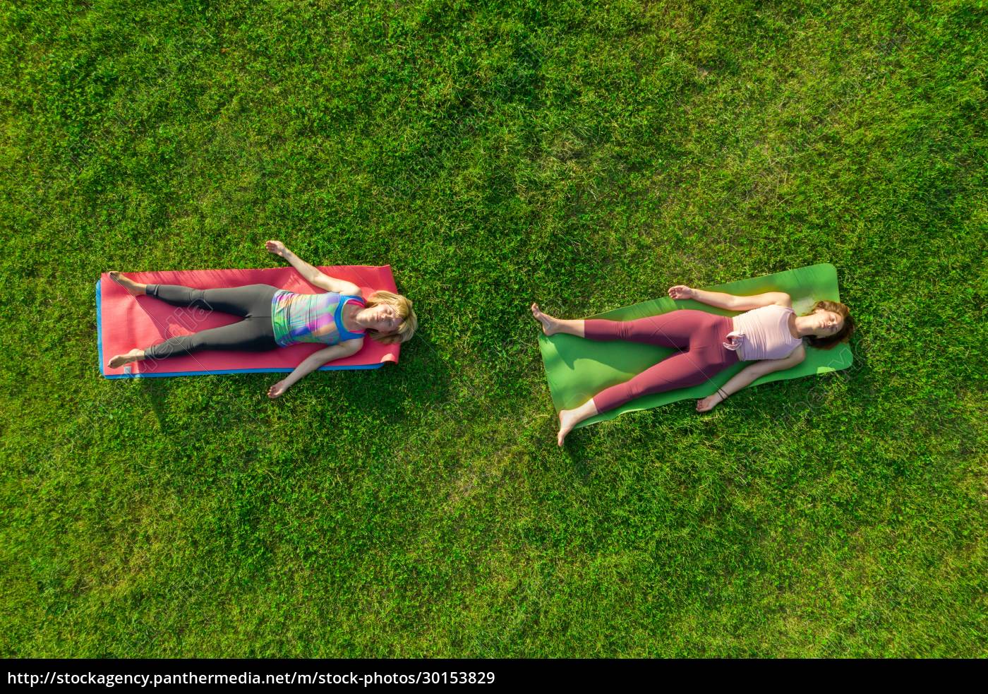 Luftaufnahme von  zwei Frauen die Yoga auf Gras im Park 